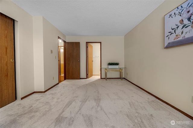 unfurnished bedroom with light colored carpet and a textured ceiling