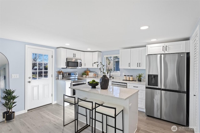 kitchen featuring a breakfast bar area, appliances with stainless steel finishes, white cabinetry, a healthy amount of sunlight, and a kitchen island