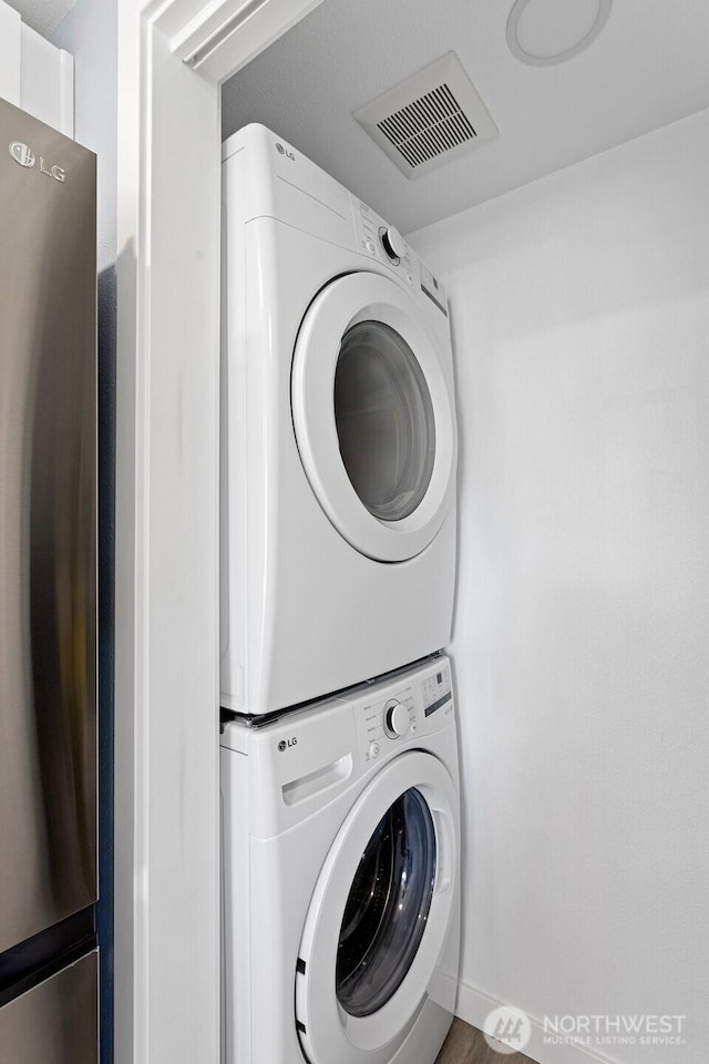 clothes washing area featuring stacked washing maching and dryer