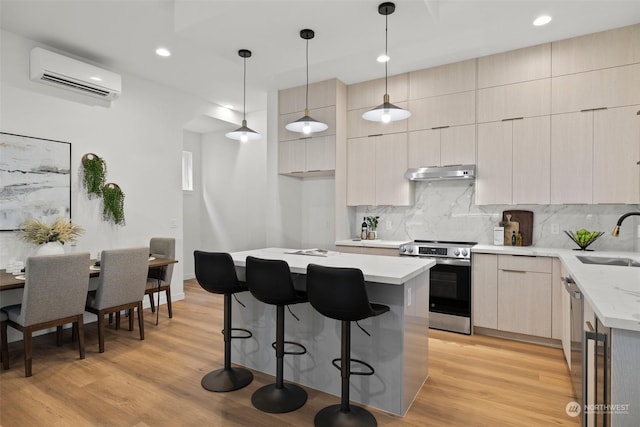 kitchen with pendant lighting, appliances with stainless steel finishes, a center island, and an AC wall unit