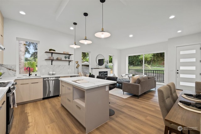 kitchen with sink, hanging light fixtures, stainless steel dishwasher, a kitchen island, and electric stove