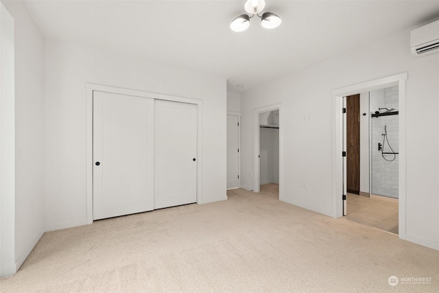 unfurnished bedroom featuring two closets, light carpet, a wall unit AC, and ensuite bath