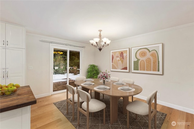 dining area with ornamental molding, a notable chandelier, and light hardwood / wood-style flooring