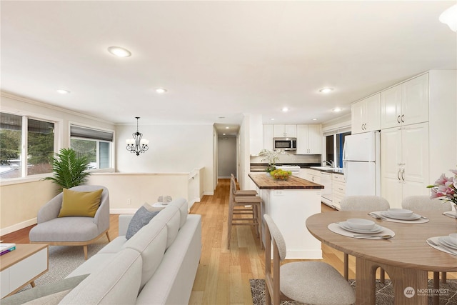 interior space with butcher block counters, white cabinetry, hanging light fixtures, white refrigerator, and light hardwood / wood-style floors