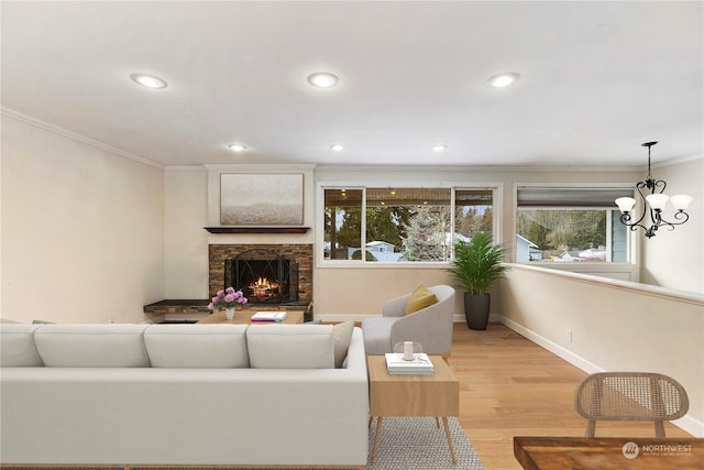 living room featuring crown molding, a fireplace, light hardwood / wood-style floors, and a chandelier