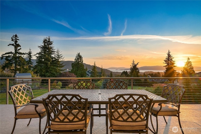 patio terrace at dusk with outdoor dining space and a mountain view