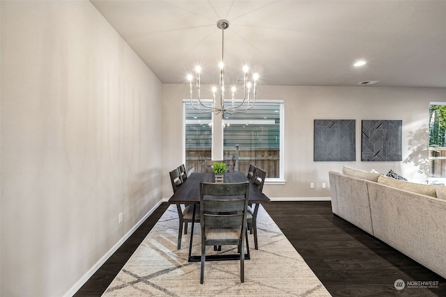 dining space with dark hardwood / wood-style floors and a notable chandelier