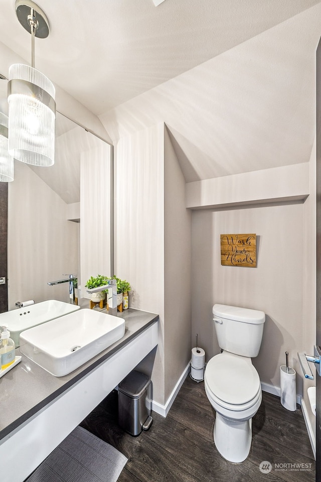 bathroom with lofted ceiling, wood-type flooring, a chandelier, and toilet