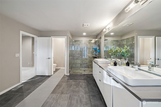 bathroom featuring a shower with door, vanity, and toilet