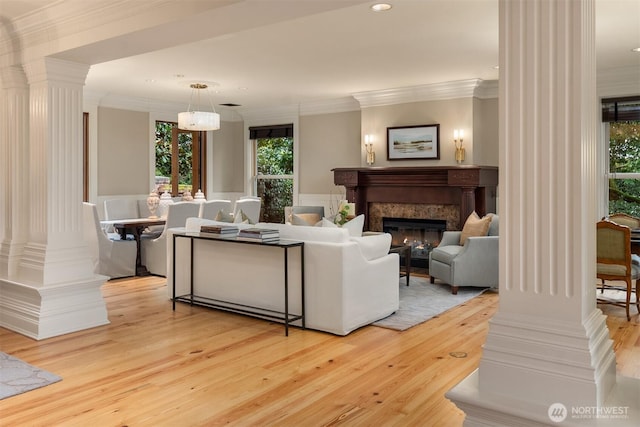 living room with ornamental molding, light hardwood / wood-style floors, a premium fireplace, and ornate columns