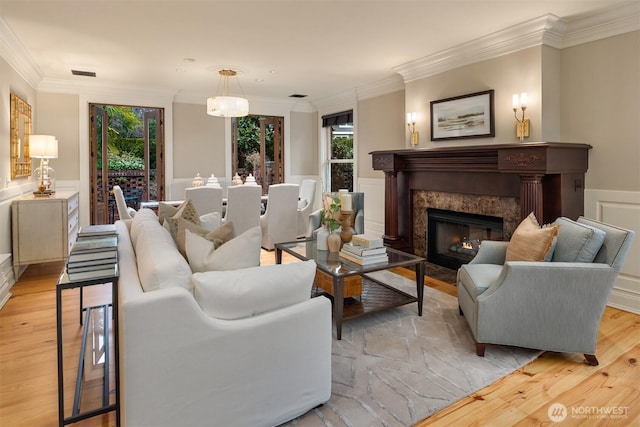 living room featuring crown molding, a wealth of natural light, a fireplace, and light hardwood / wood-style floors