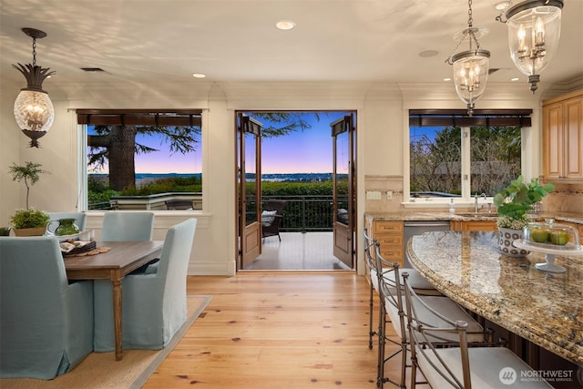 dining area with an inviting chandelier, sink, and light hardwood / wood-style flooring