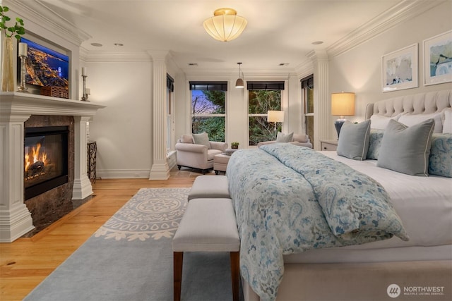 bedroom featuring decorative columns, ornamental molding, and hardwood / wood-style floors