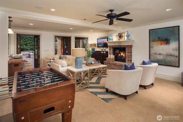 living room with crown molding, ceiling fan, a fireplace, and light carpet