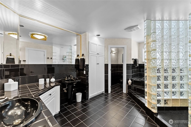 bathroom featuring tile patterned flooring, sink, tile walls, and walk in shower