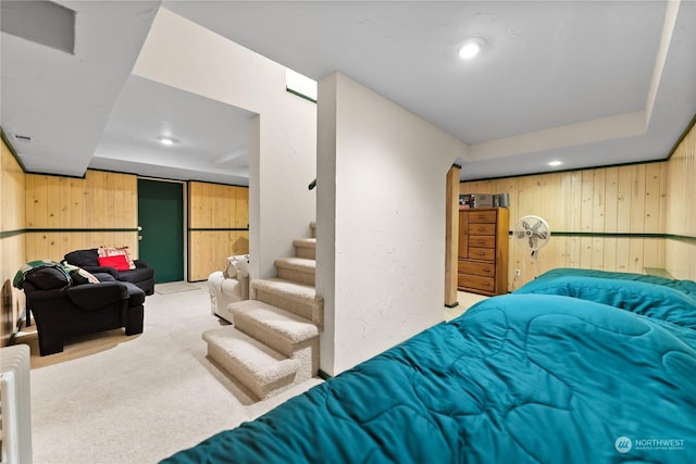 bedroom with light carpet and wooden walls