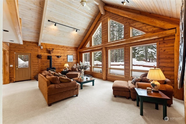 carpeted living room with a wealth of natural light, beamed ceiling, and a wood stove