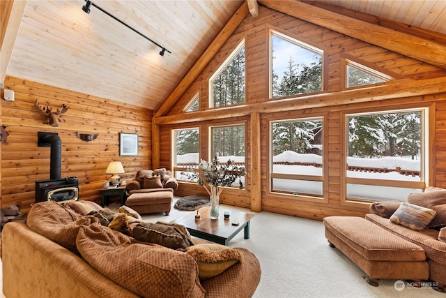 carpeted living room featuring a wood stove, track lighting, wooden ceiling, and high vaulted ceiling