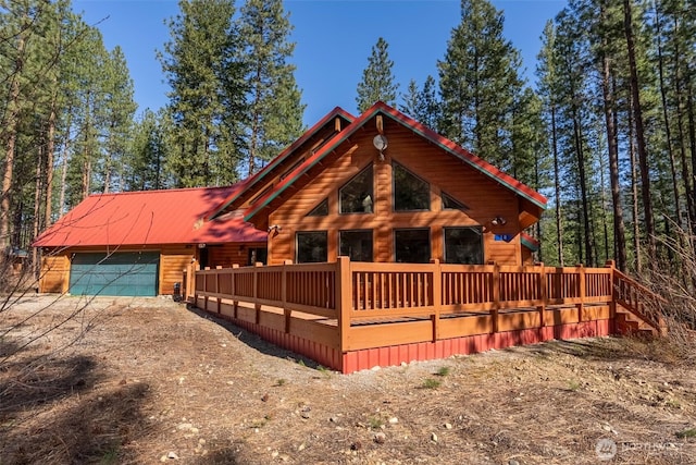 view of front of house with an attached garage, log siding, and driveway