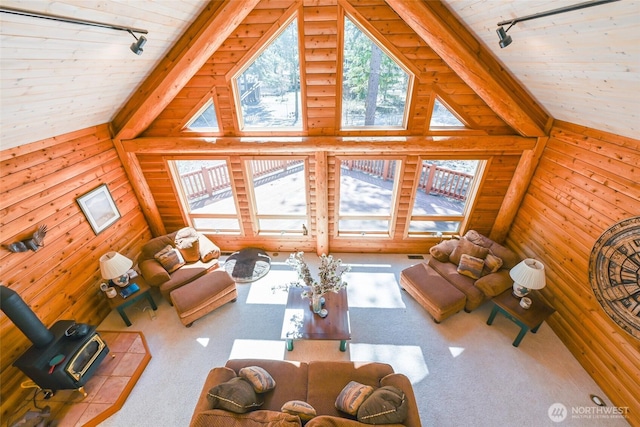 living room with track lighting, carpet, a wood stove, and lofted ceiling with beams
