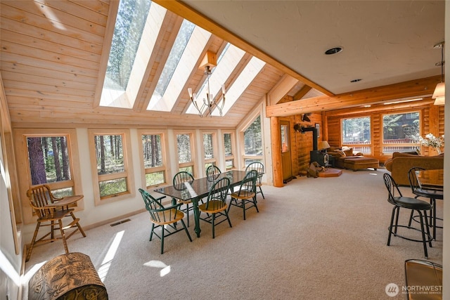 sunroom / solarium featuring visible vents, carpet, a wood stove, and vaulted ceiling with skylight