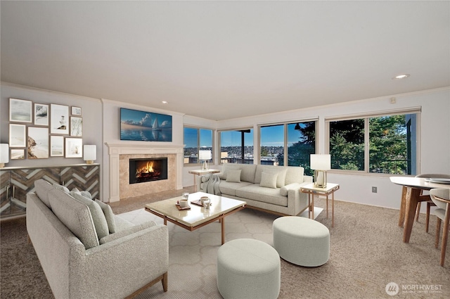 living room with a tiled fireplace, crown molding, and light colored carpet