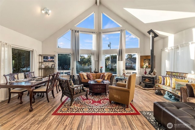 living room with high vaulted ceiling, wood finished floors, and a wood stove