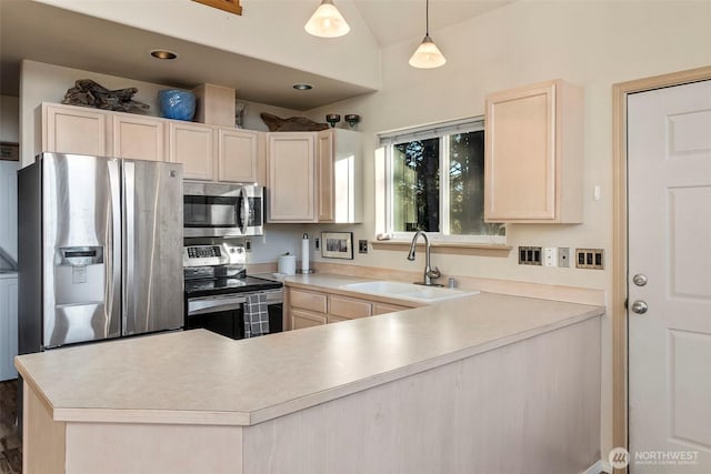 kitchen with light brown cabinetry, a peninsula, stainless steel appliances, and a sink