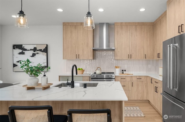 kitchen with appliances with stainless steel finishes, sink, light brown cabinetry, and wall chimney exhaust hood