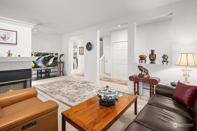 living room featuring a tiled fireplace and ceiling fan