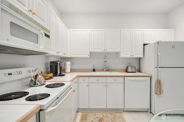 kitchen with sink, white appliances, tile counters, and white cabinets