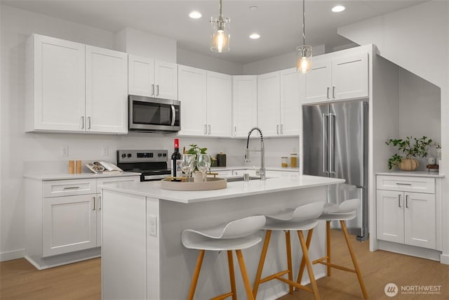 kitchen with appliances with stainless steel finishes, light wood-type flooring, light countertops, and a sink