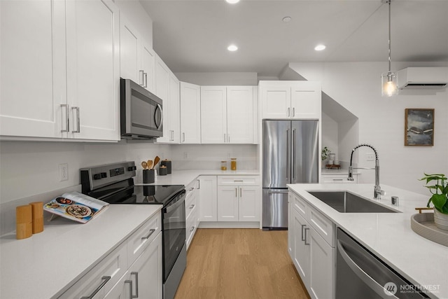 kitchen featuring stainless steel appliances, light countertops, a sink, and a wall mounted AC