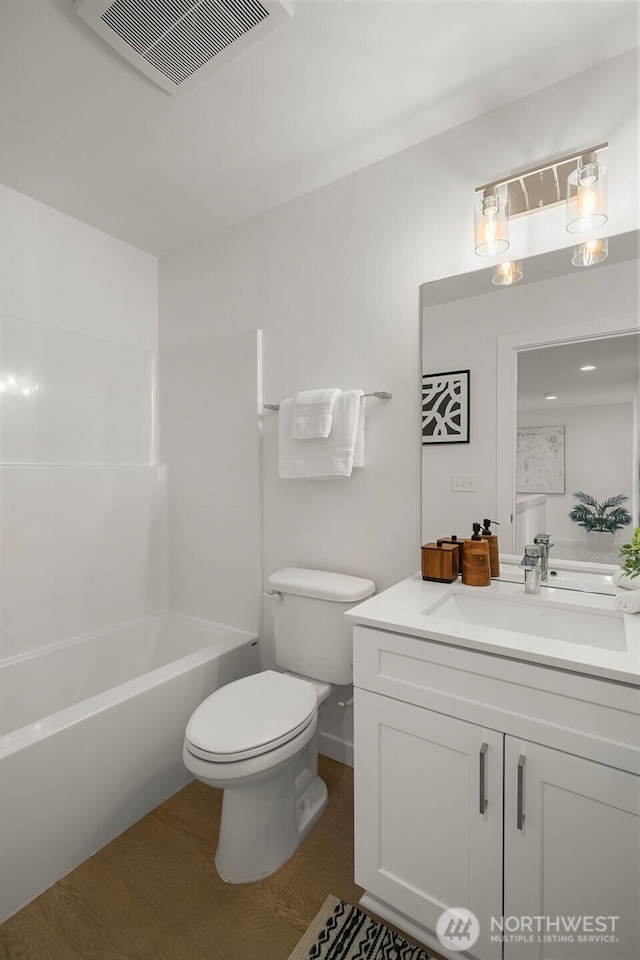 bathroom featuring visible vents, toilet, wood finished floors, bathtub / shower combination, and vanity