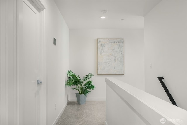 hall featuring carpet floors, recessed lighting, baseboards, and an upstairs landing