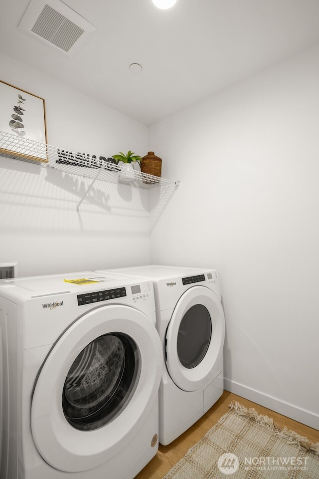 clothes washing area featuring laundry area, separate washer and dryer, light wood-type flooring, and visible vents