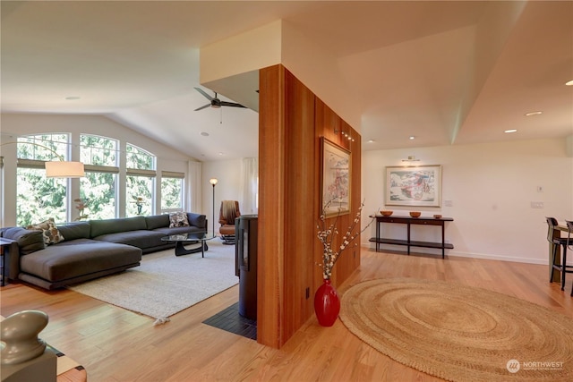 living room featuring ceiling fan, lofted ceiling, and light hardwood / wood-style flooring