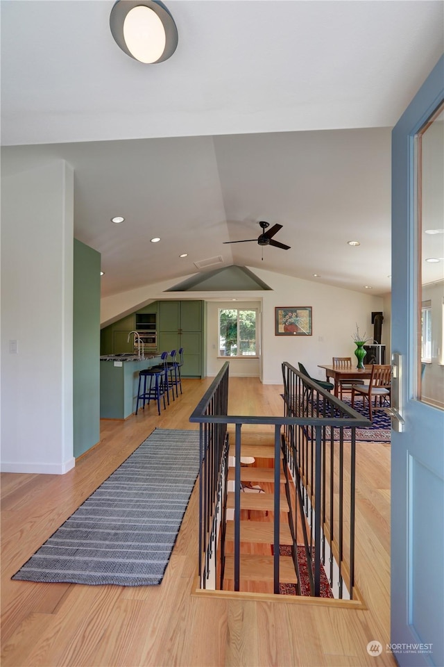 staircase featuring lofted ceiling, wood-type flooring, and sink