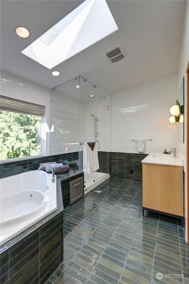 bathroom with tile walls, vanity, a skylight, and plus walk in shower