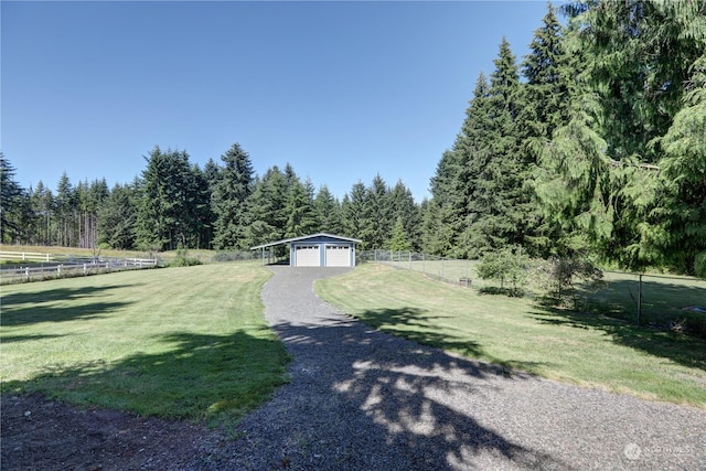 view of yard featuring a garage, an outdoor structure, and a rural view