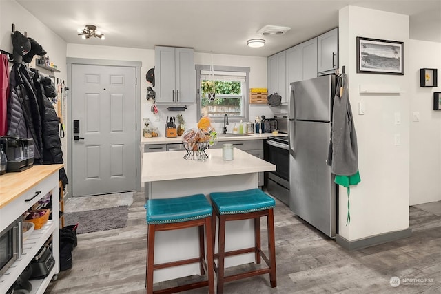 kitchen with a center island, light hardwood / wood-style floors, a breakfast bar, and appliances with stainless steel finishes