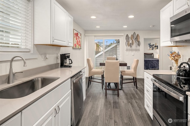 kitchen with white cabinetry, appliances with stainless steel finishes, dark wood-type flooring, and sink