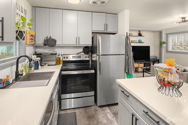 kitchen featuring white cabinetry, sink, stainless steel appliances, and light hardwood / wood-style floors