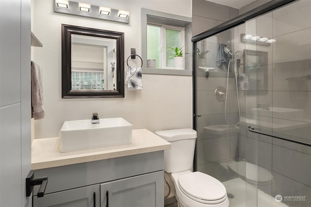 bathroom featuring an enclosed shower, vanity, and toilet