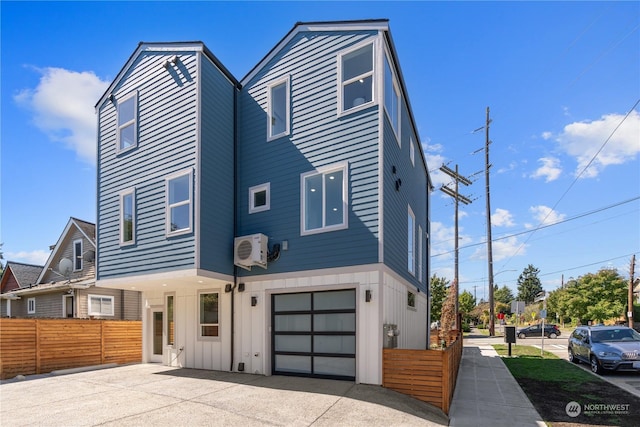 view of front of home featuring a garage and a wall mounted AC