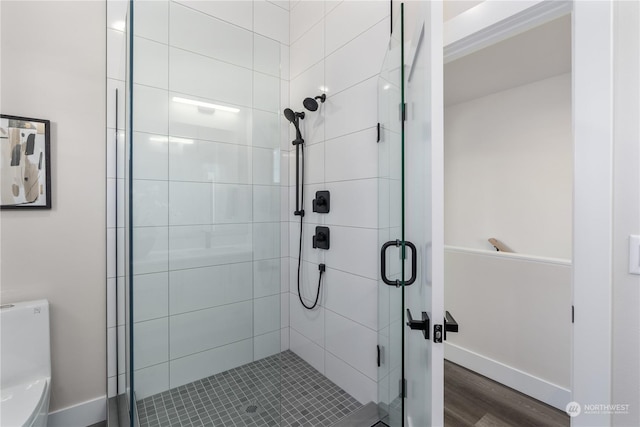 bathroom with hardwood / wood-style flooring, toilet, and a shower with door