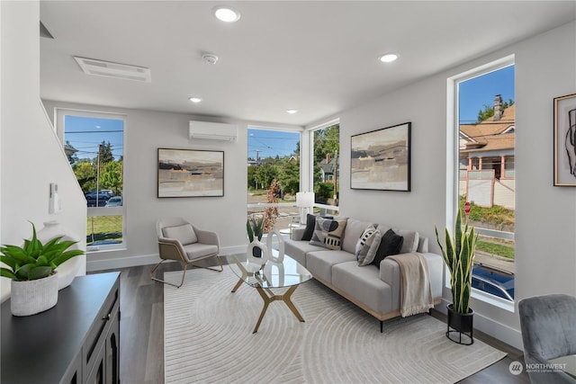 living room featuring hardwood / wood-style floors, a wall unit AC, and a wealth of natural light