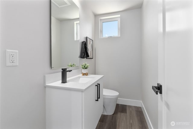 bathroom with vanity, toilet, and hardwood / wood-style floors