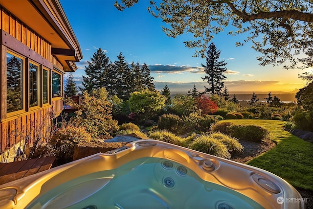 pool at dusk with a hot tub