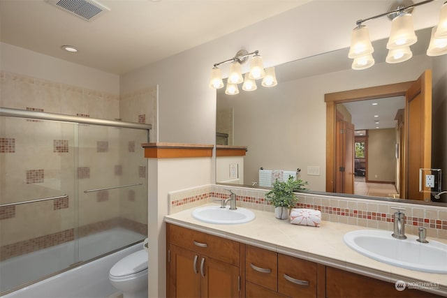 full bathroom featuring bath / shower combo with glass door, toilet, vanity, and decorative backsplash